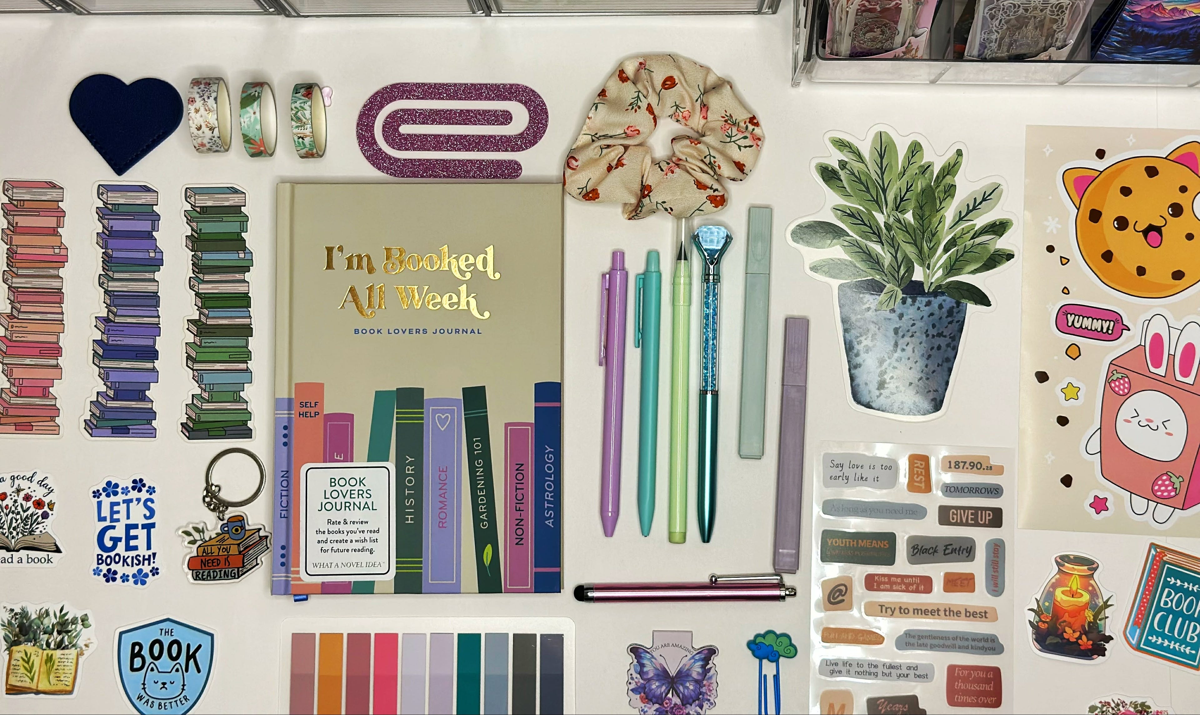 Collection of stationery items including books, pens, and decorative elements on a white surface.