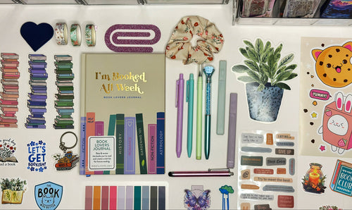 Collection of stationery items including books, pens, and decorative elements on a white surface.