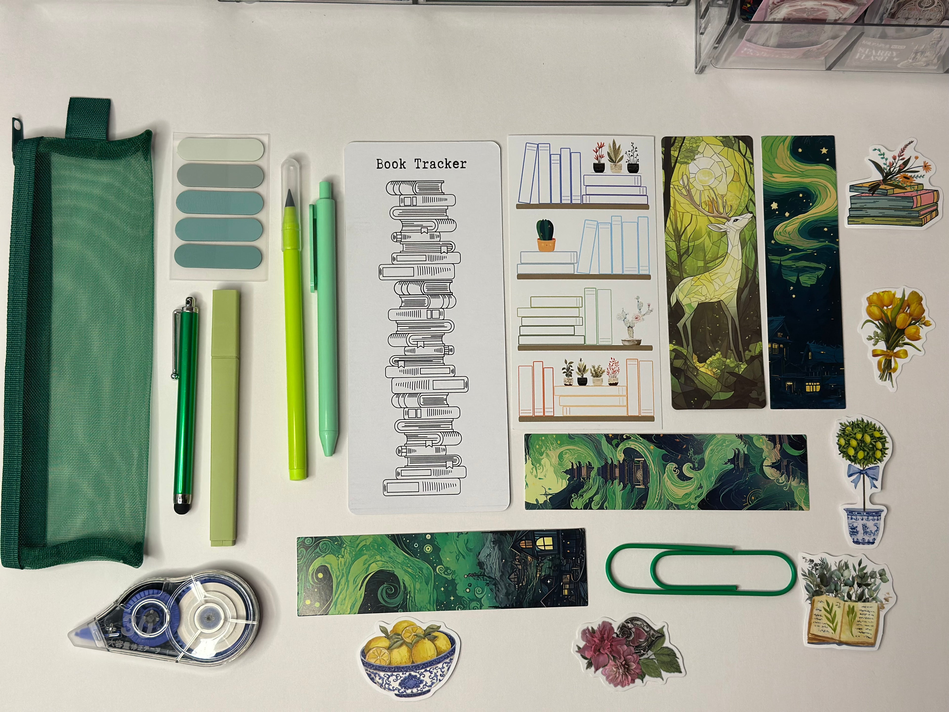 Collection of stationery items including pens, a pencil case, and decorative stickers on a white surface.
