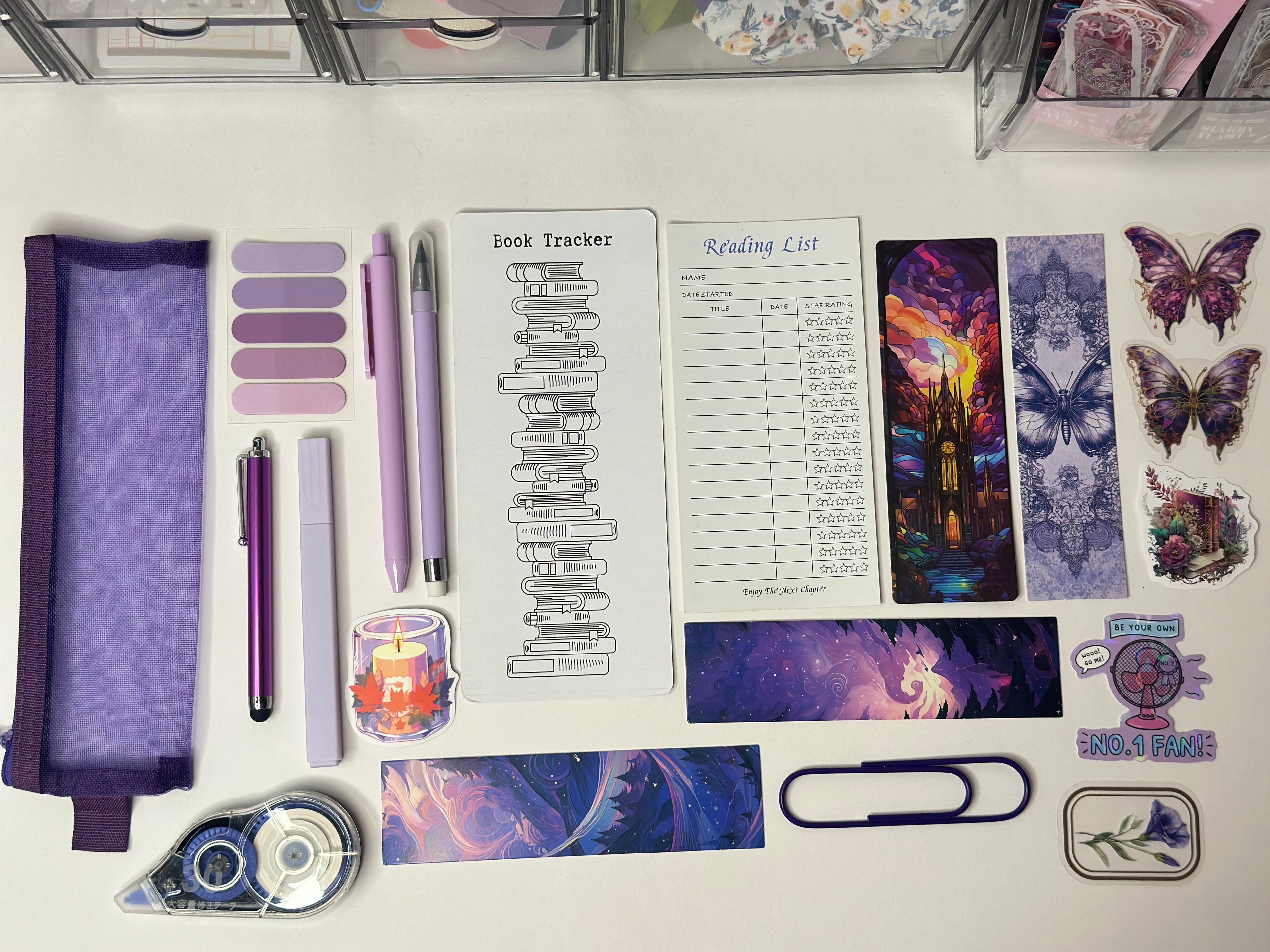 Assorted stationery items including a purple pencil case, pens, stickers, and a reading list on a white surface.